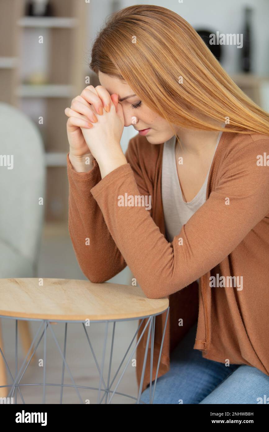 Seitenansicht einer schönen jungen Frau, die zu Hause betet Stockfoto