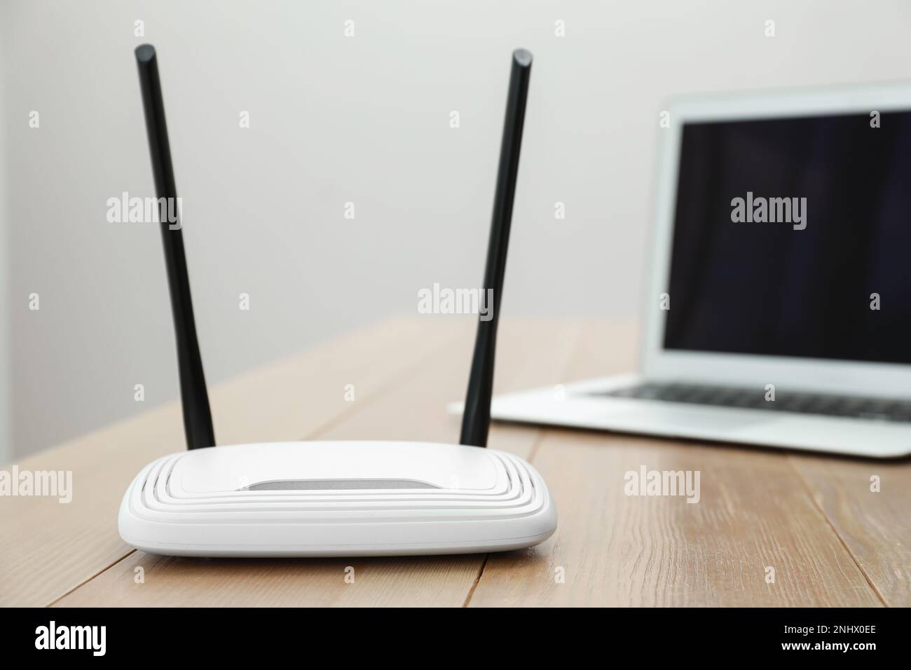 Moderner WLAN-Router und Laptop auf Holztisch im Innenbereich Stockfoto