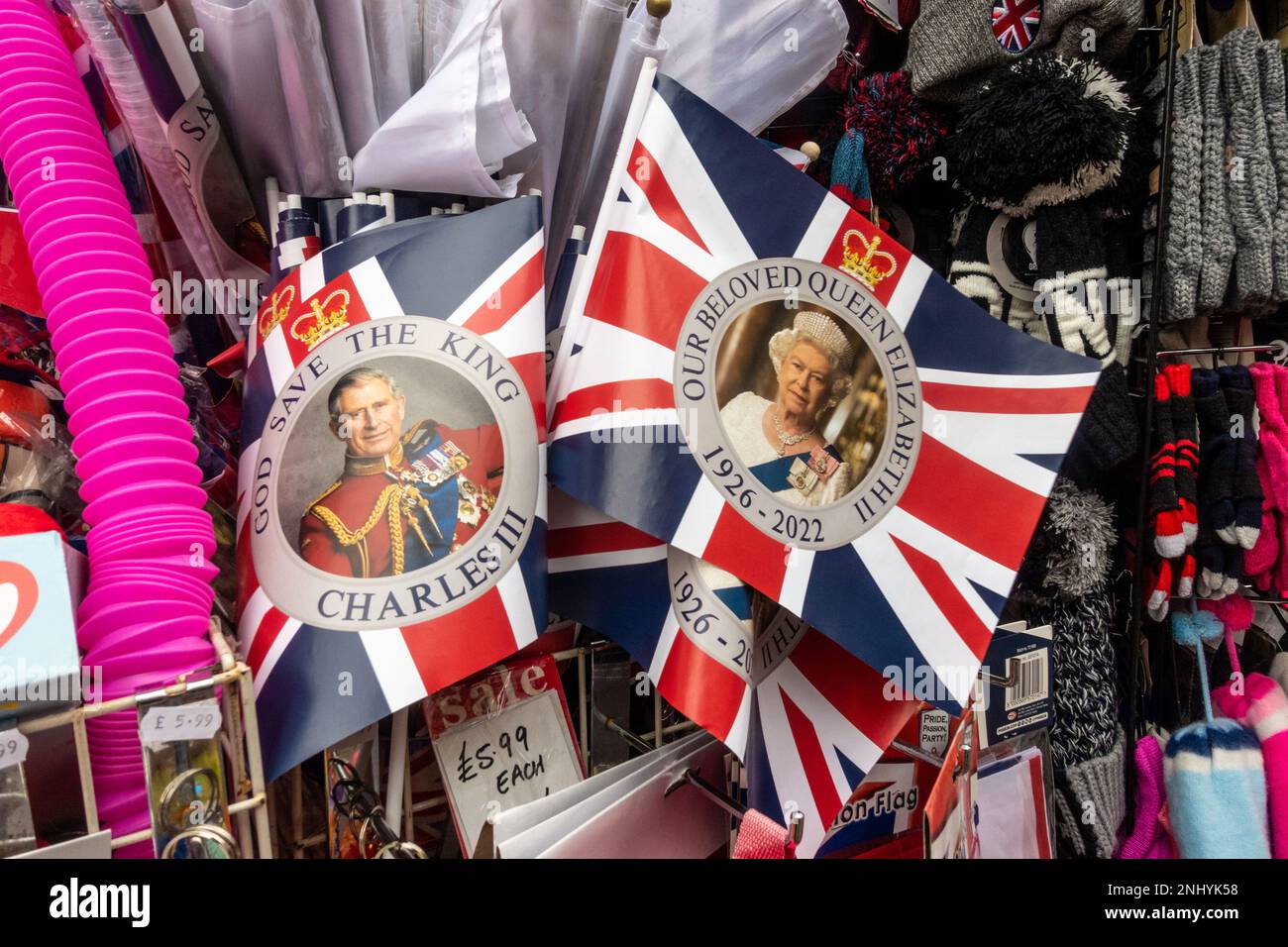 Union-Jack-Flaggen mit Porträts der britischen Monarchie unter Souvenirs, die in einem Souvenirladen verkauft werden Stockfoto