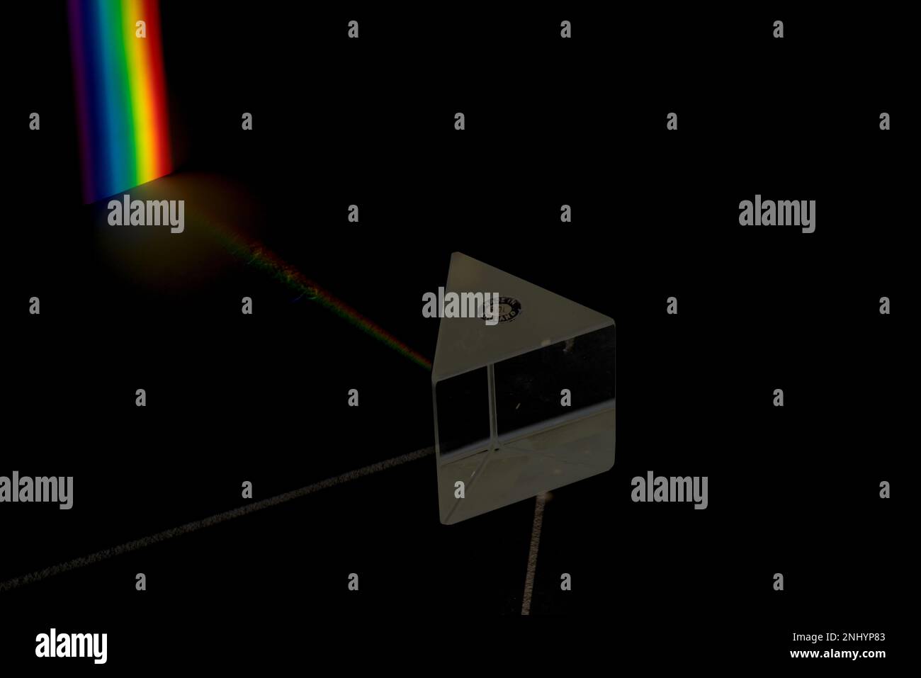 Ein weißer Lichtstrahl, der durch ein gleichseitiges Glasprisma, Dispersion, geteilt wird, in die Wellenlängen des Spektrums, die auf eine Leinwand projiziert werden, Regenbogenlichter Stockfoto