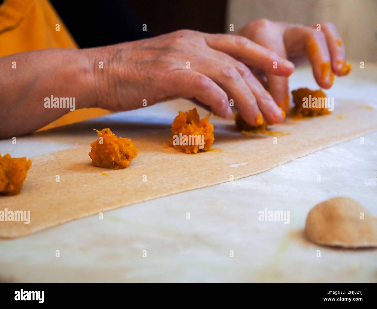 Seniorin bereitet gefüllte Kürbis-Ravioli-Tortelli mit italienischem Vollkornmehl zu Hause zu, hausgemachtes Essenskonzept Stockfoto