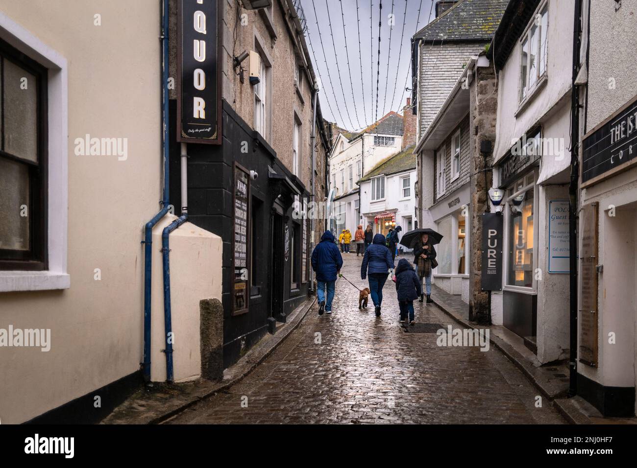 Urlauber, die in der Nebensaison in St. Ives in Cornwall, England, an der Fore Street entlang spazieren. Stockfoto