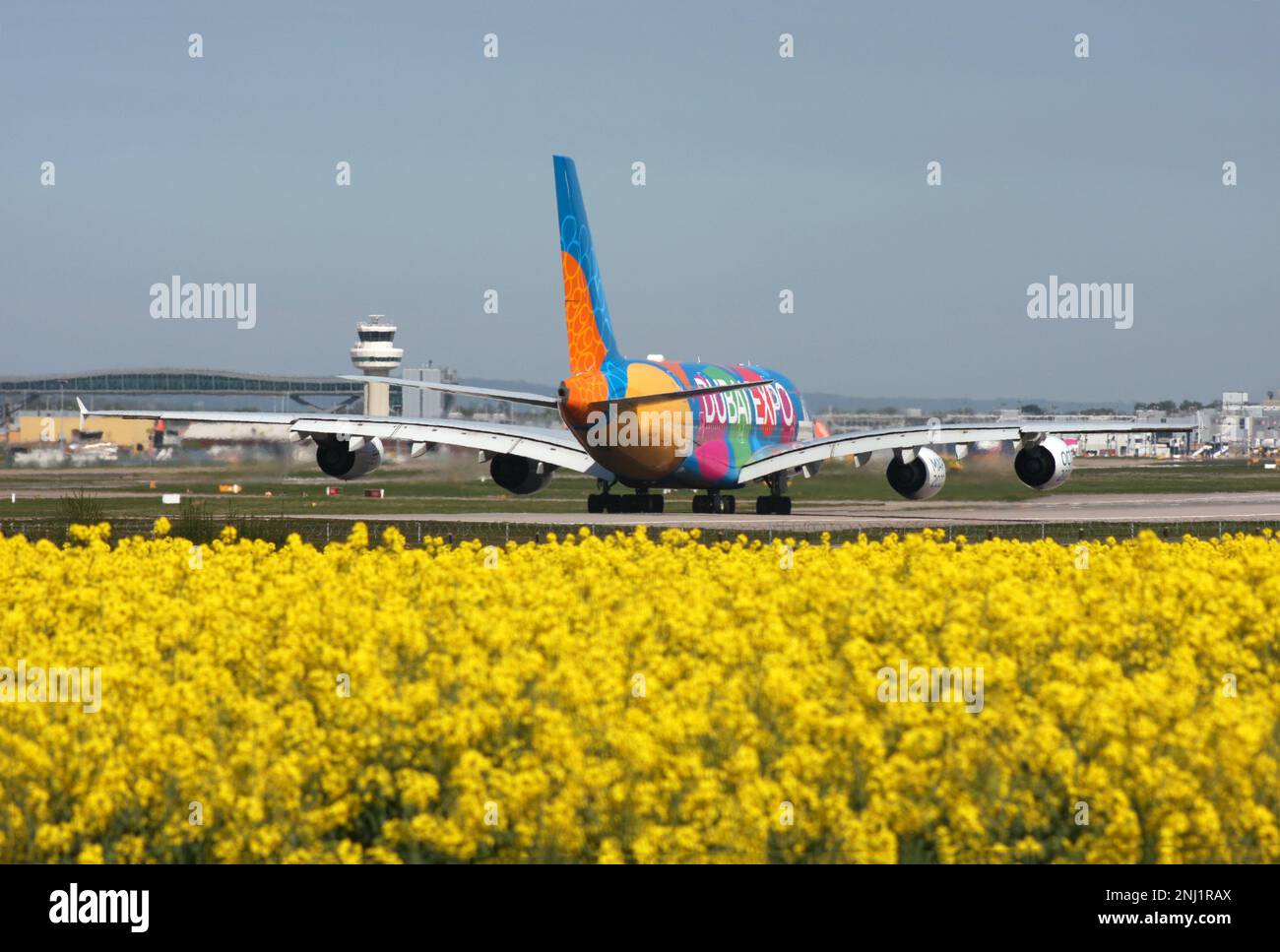 A380 Emirate in einer speziellen Dubai Expo-Lackierung stehen Schlange, um in Gatwick mit Blick auf den Kontrollturm und die Luftbrücke sowie die Rapsblume abzuheben Stockfoto