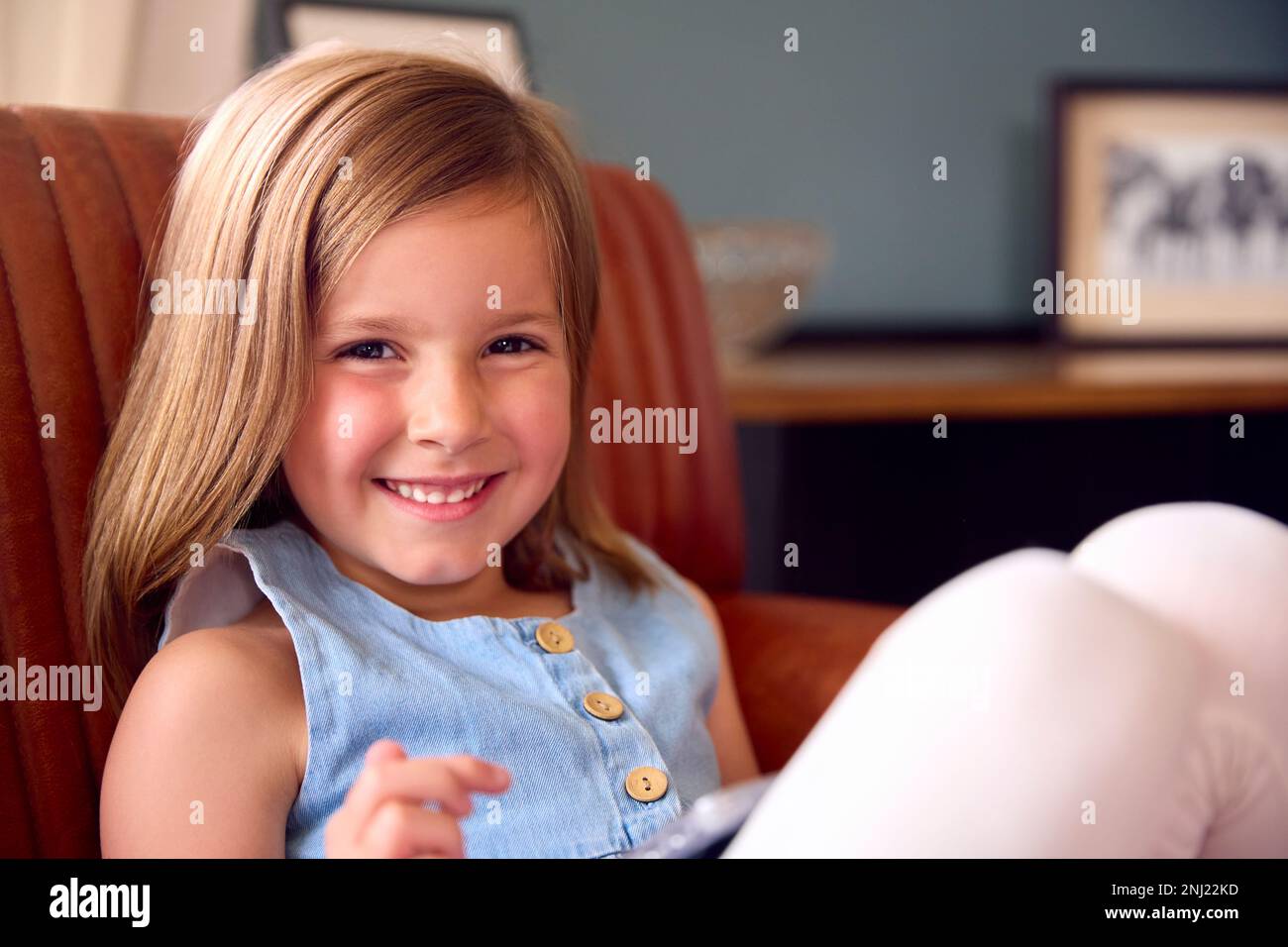 Portrait Eines Lächelnden Jungen Mädchens Zu Hause, Das Auf Einem Stuhl Sitzt Stockfoto