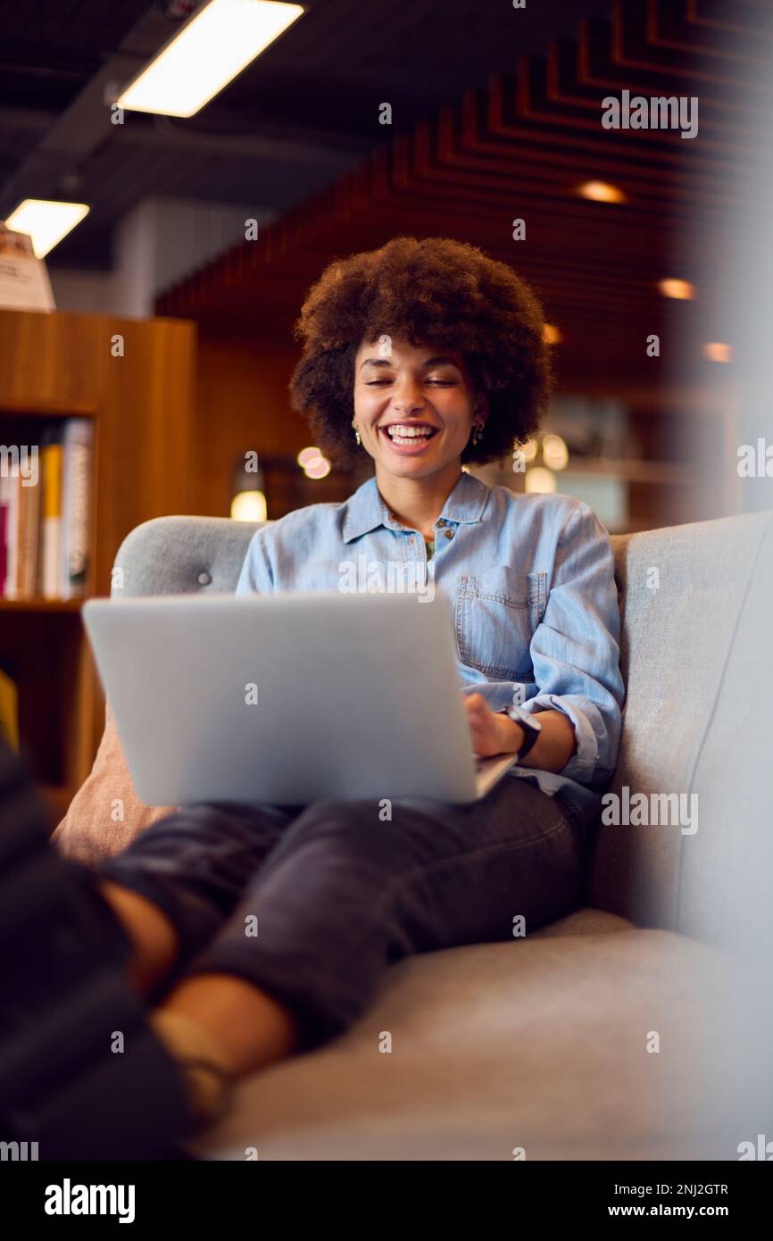 Junge Geschäftsfrau In Einem Modernen Großraumbüro, Die An Einem Laptop In Einem Zwanglosen Sitzbereich Arbeitet Stockfoto