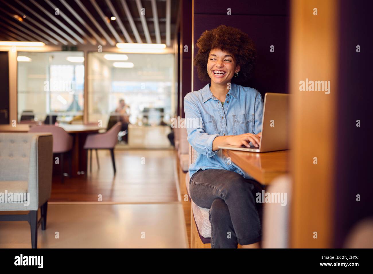 Junge Geschäftsfrau In Einem Modernen Großraumbüro, Die An Einem Laptop In Einer Sitzkonsole Arbeitet Stockfoto
