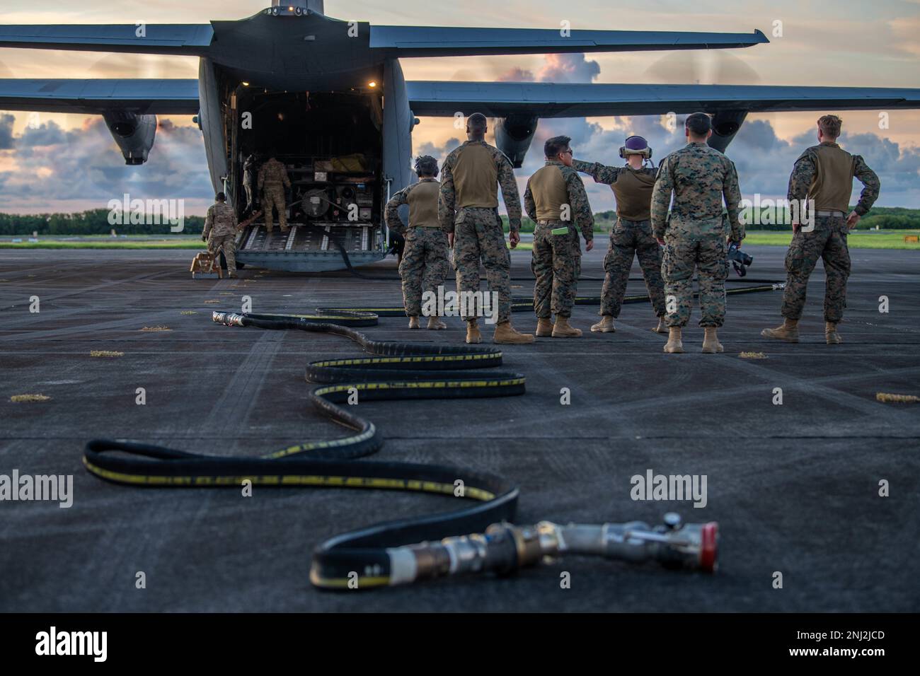 Flugzeuge der 374. Logistics Readiness Squadron und Marines stehen vor einem C-130J Super Hercules, der der 36. Airlift Squadron am Iwo Jima Airport, Japan, am 4. August 2022 zugeteilt wurde. Der 36. AS und der 374. LRS lieferten Kraftstoff, um Marines bei der Einrichtung eines Tankpunktes direkt nach der Landung zu unterstützen und zu demonstrieren, wie Flugzeuge sich selbst bedienen können in rauen Umgebungen. Stockfoto