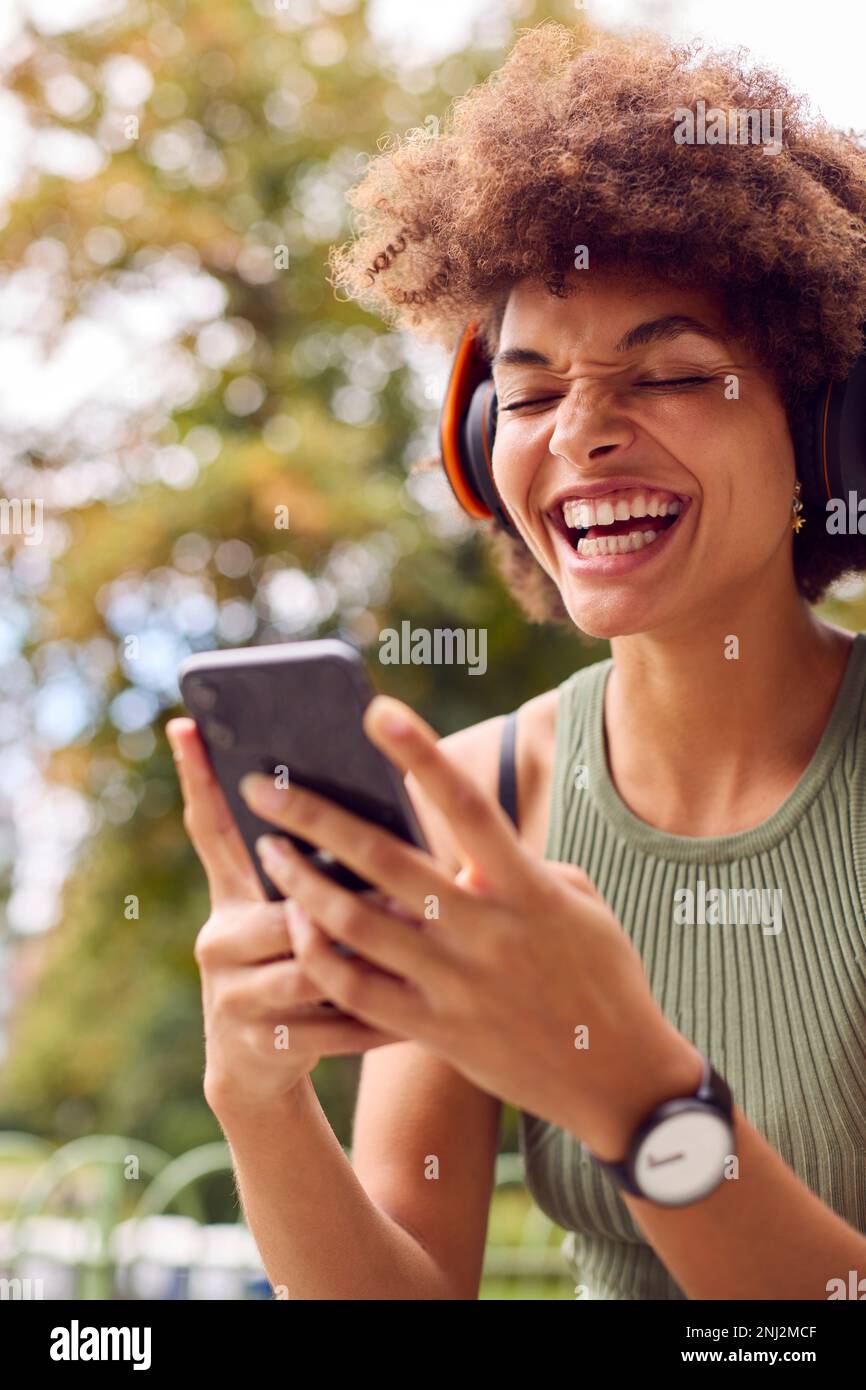 Junge Frau Im Freien Mit Kabellosen Kopfhörern, Streaming-Show Vom Mobiltelefon Stockfoto