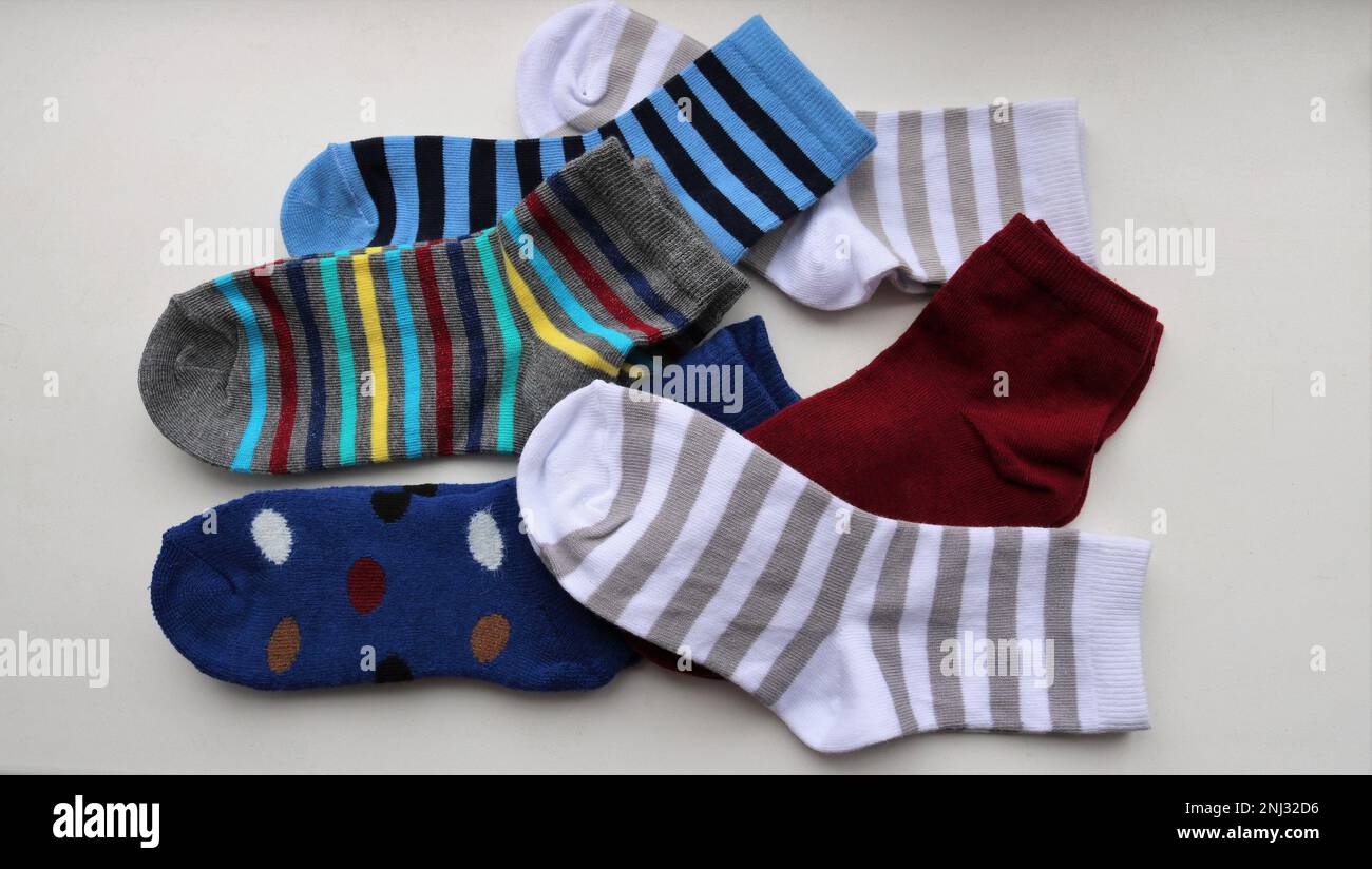Stilleben von mehrfarbigen Baumwollsocken für Kinder, die zufällig auf einer leichten Oberfläche liegen, eine chaotische Anordnung von Kleidungsstücken für Kinder, neue kleine Socken Stockfoto