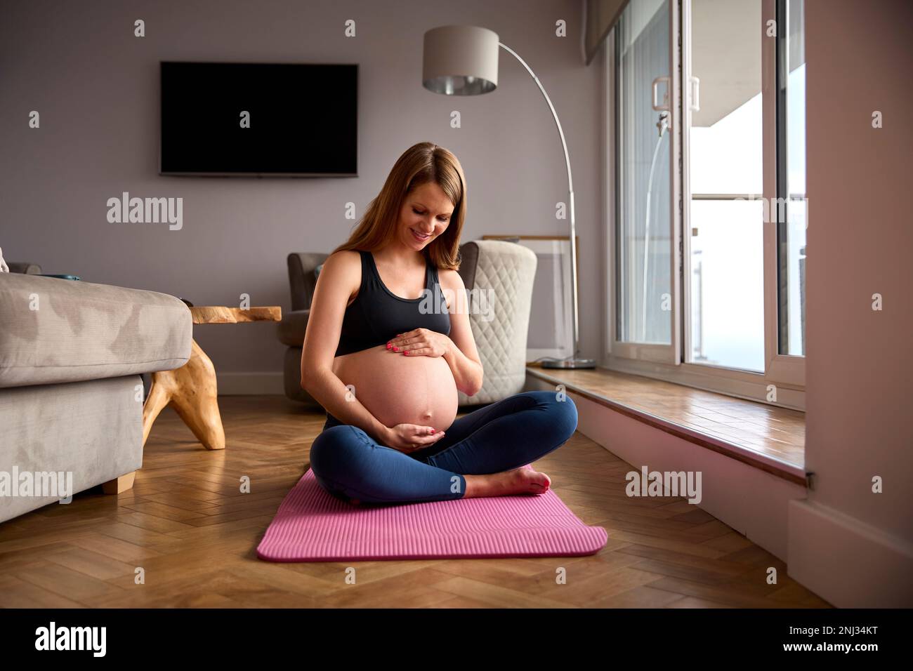 Schwangere Frau Trägt Fitnesskleidung Auf Der Trainingsmatte Zu Hause Beim Yoga Stockfoto