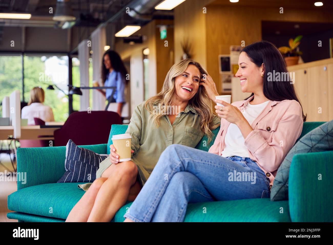 Zwei Geschäftsfrauen, Die Sich Informell Im Sitzbereich Von Modern Office Treffen Stockfoto
