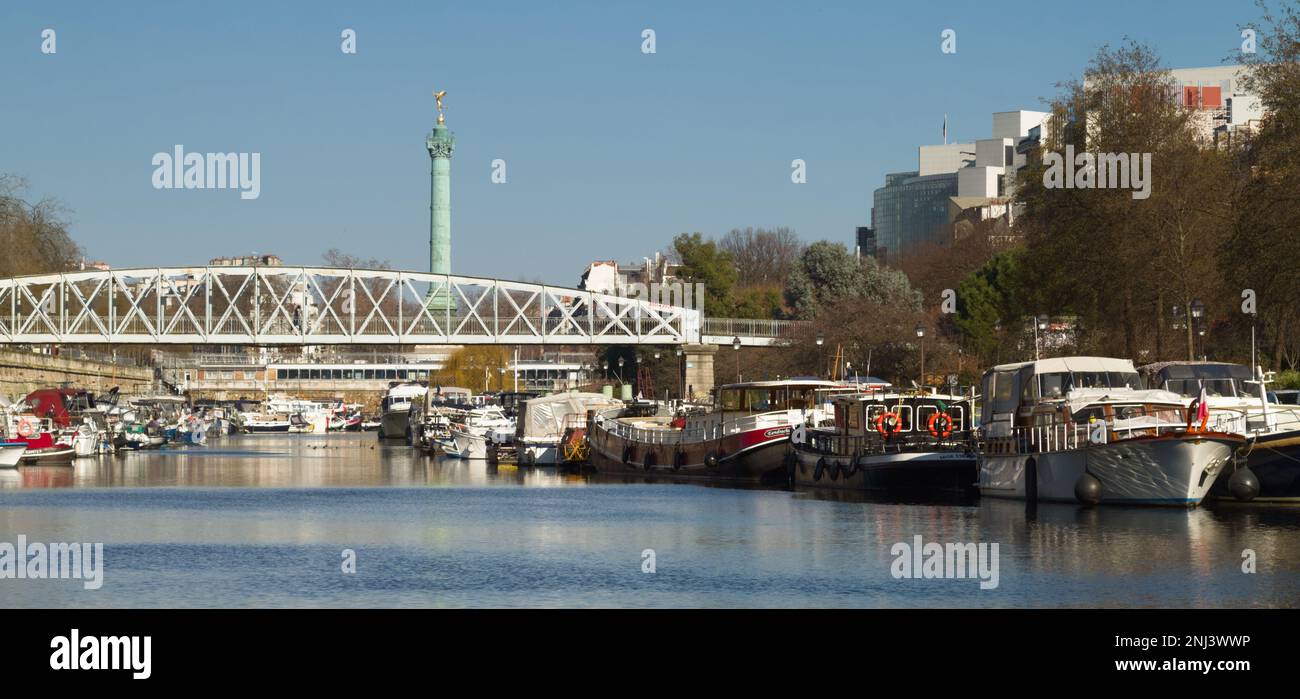 Hausboote im Canal Saint Martin und im Basin de l'Arsenal mit Passerelle De Mornay und der Juli-Säule im Hintergrund, Paris Stockfoto