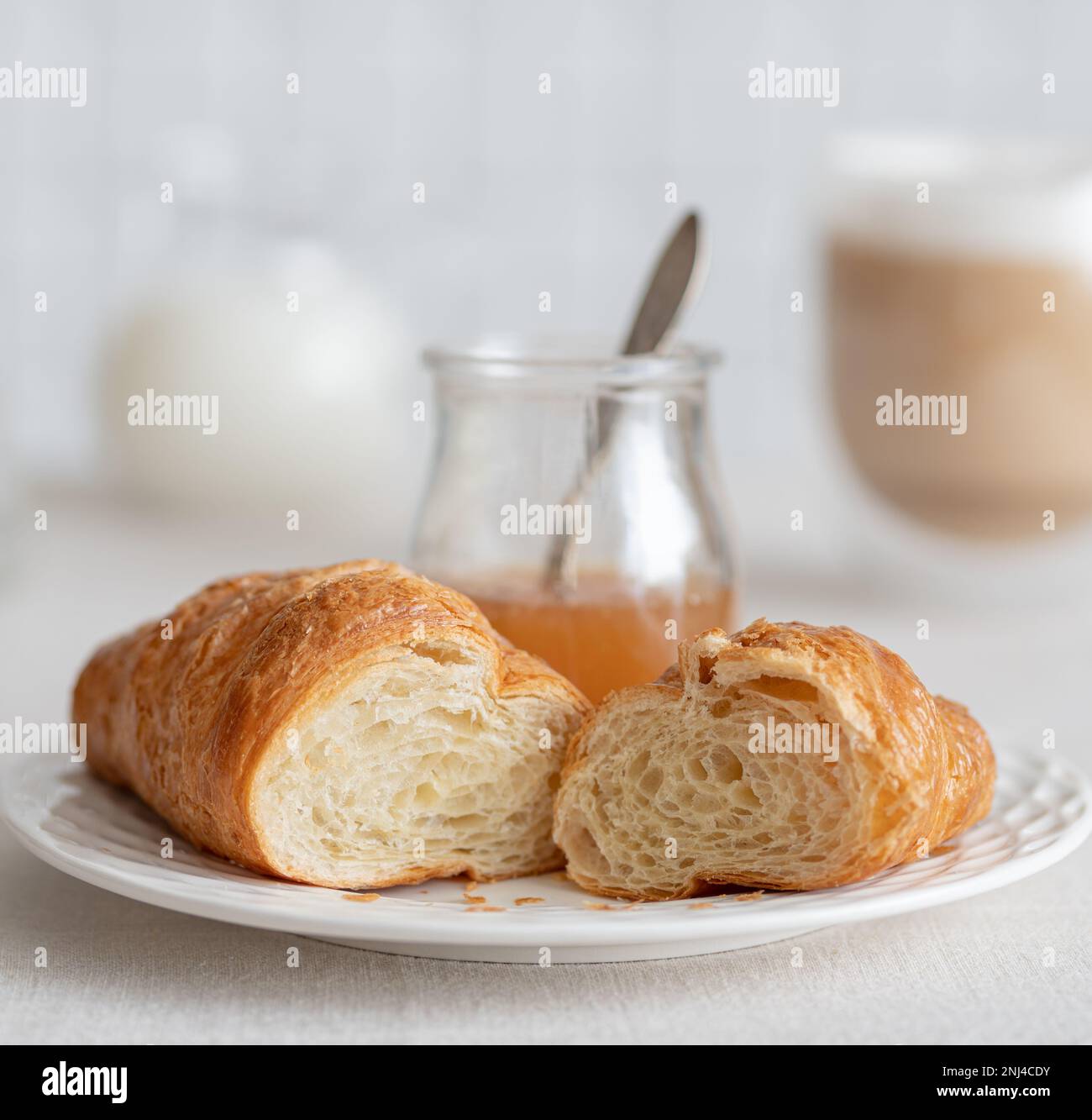 Croissant mit Birnenmarmelade zum Frühstück mit einer Tasse Kaffee mit Milch. Französisches Frühstück Stockfoto