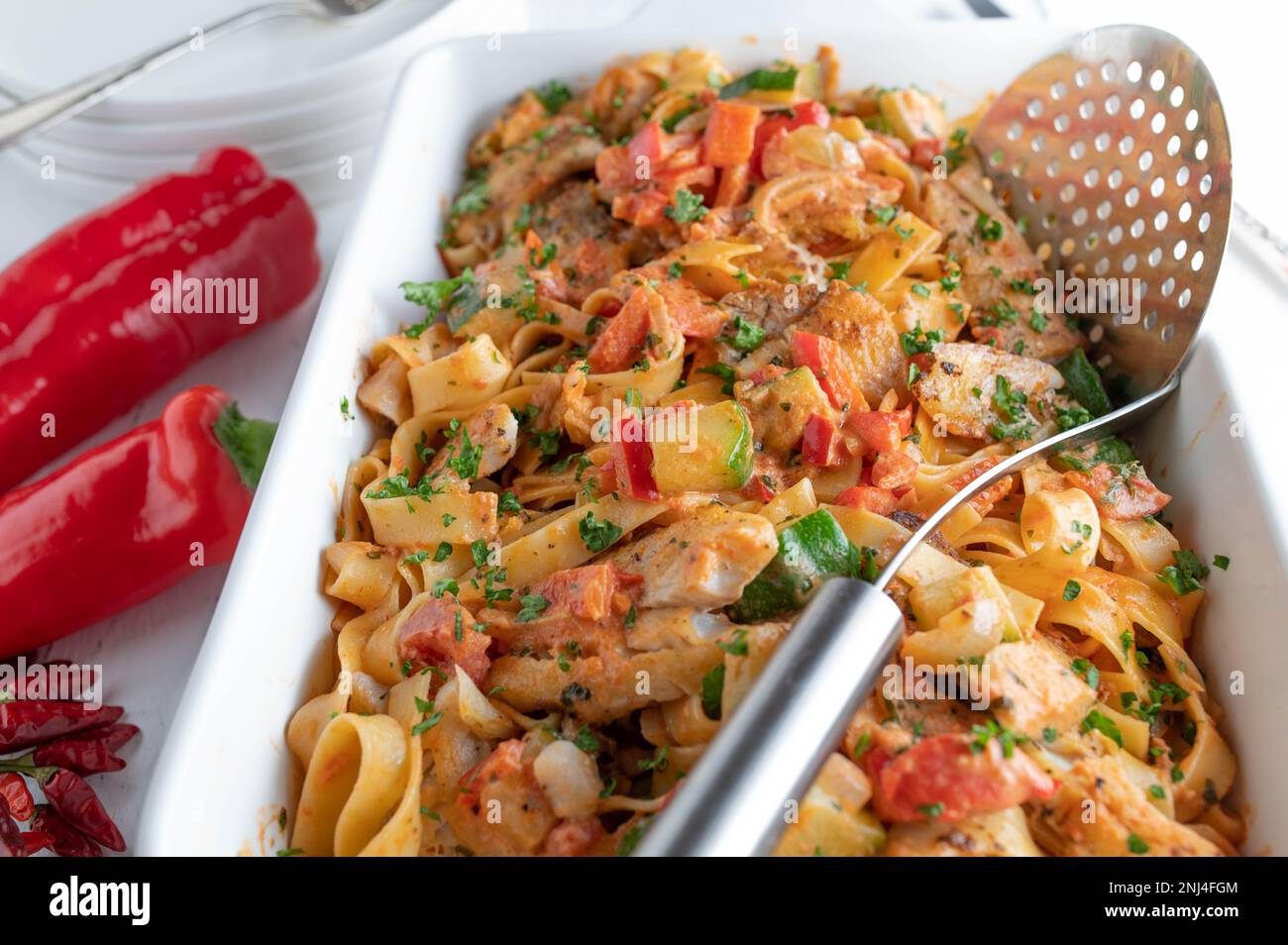 Fisch mit Pasta und mediterranem Gemüse in einem weißen Backblech Stockfoto