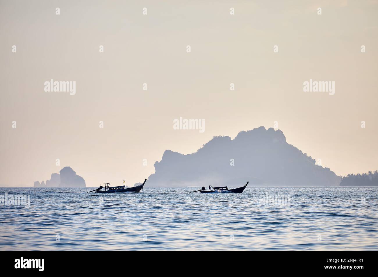 Traditionelle Langboote in Silhouette in der Nähe tropischer Inseln bei Sonnenuntergang in der Andamanensee, Südthailand Stockfoto