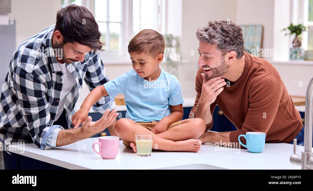 Same-Sex-Familie Mit Zwei Vätern In Der Küche, Mit Sohn, Der An Der Theke Sitzt Stockfoto