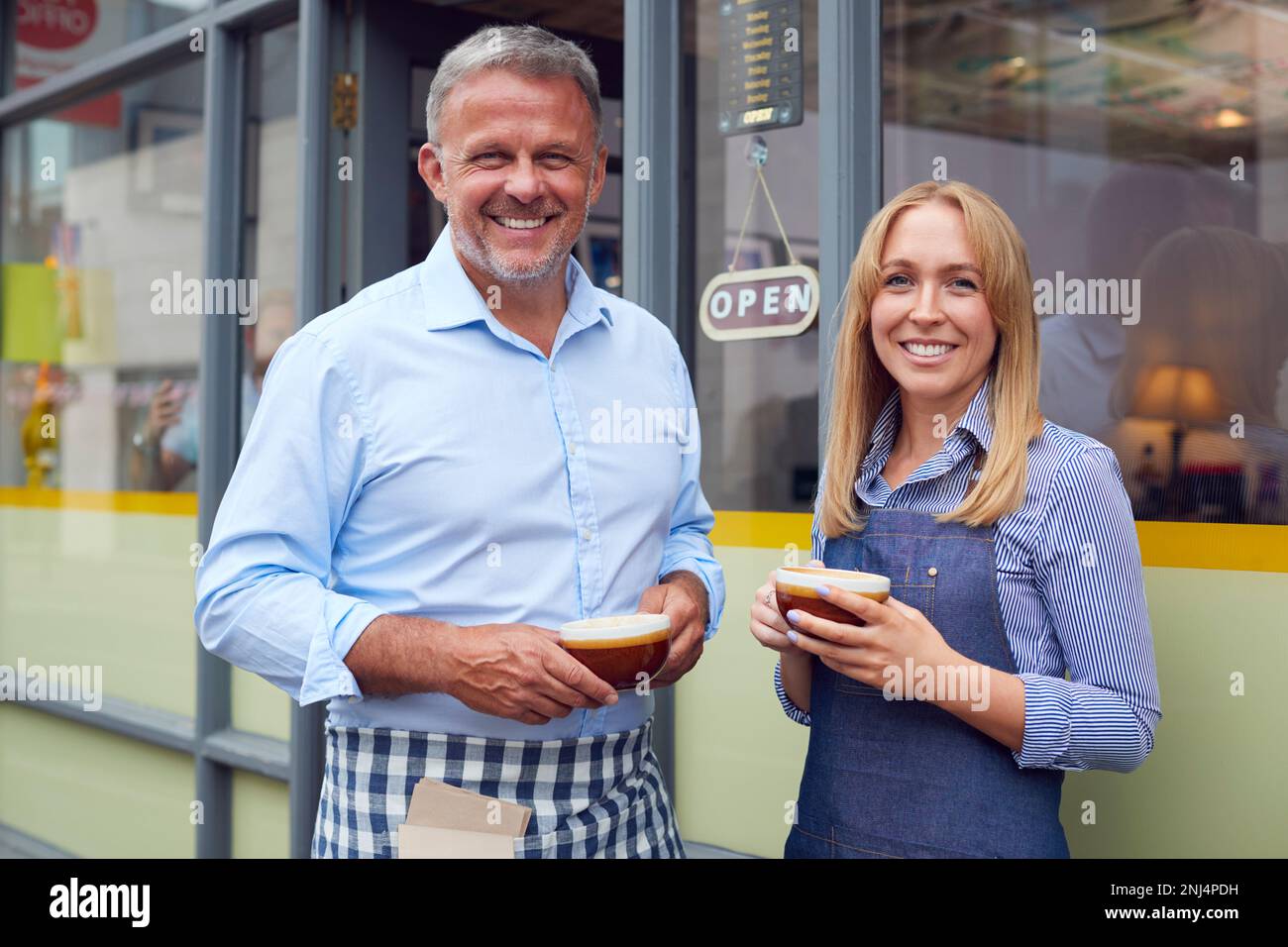 Porträt Von Männlichen Und Weiblichen Eigentümern Oder Mitarbeitern, Die Vor Dem Coffee Shop Stehen Und Heiße Getränke Anbieten Stockfoto