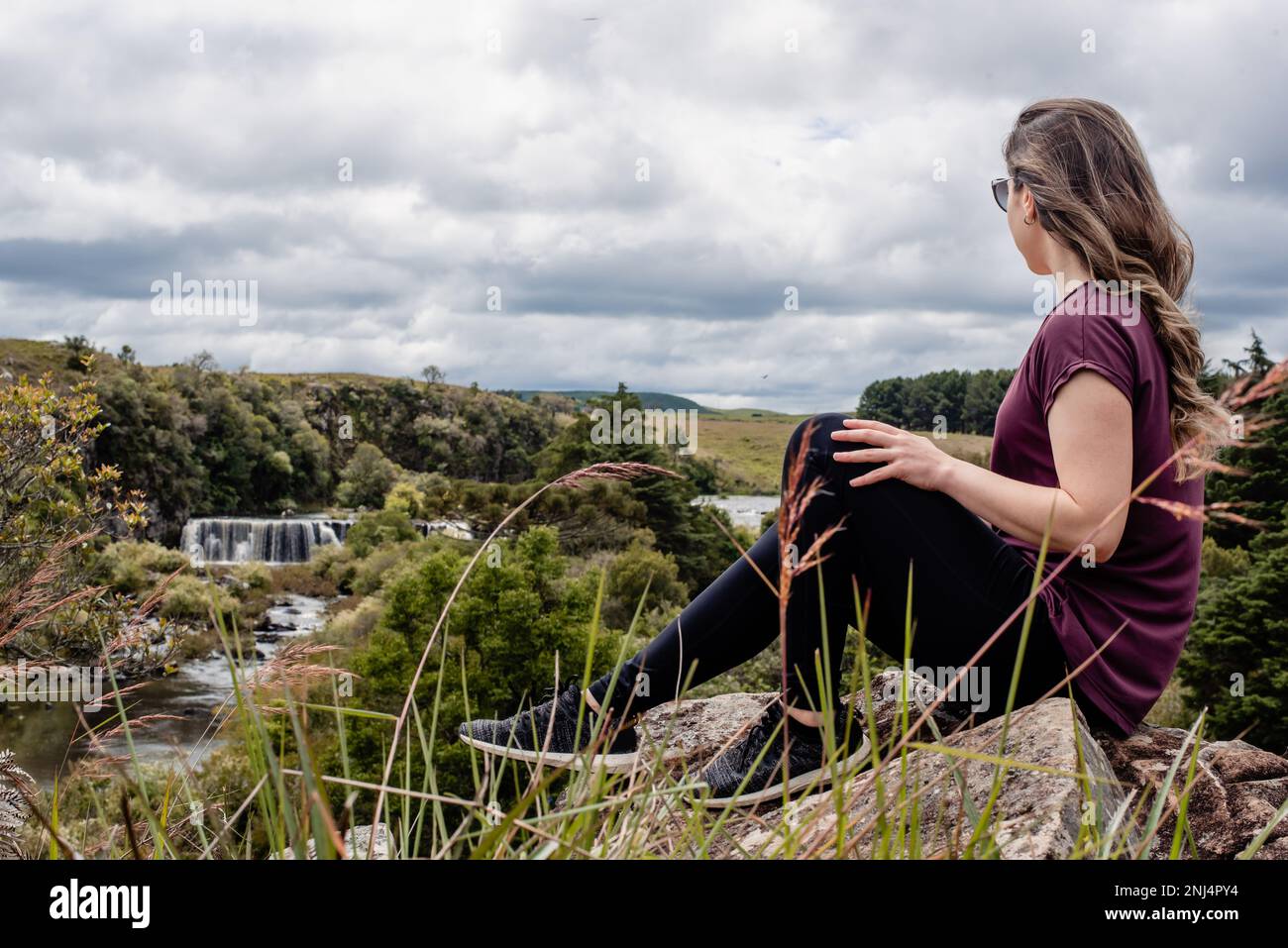 Abenteuerlustige Frau, die auf den Wasserfall blickt Stockfoto