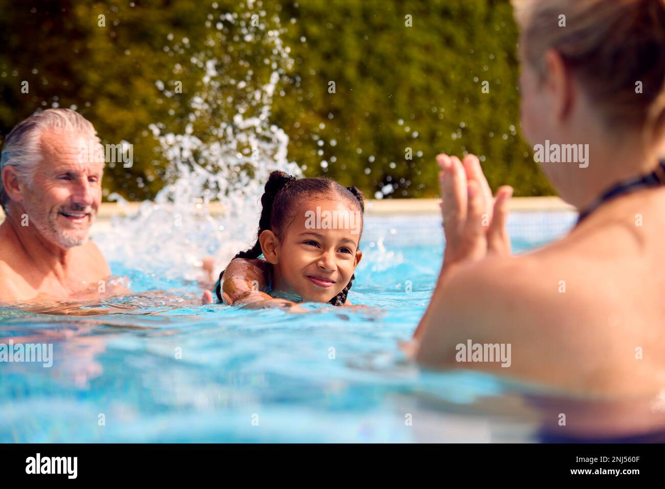 Großeltern Bringen Ihrer Enkelin Bei, Im Familienurlaub Im Pool Zu Schwimmen Stockfoto