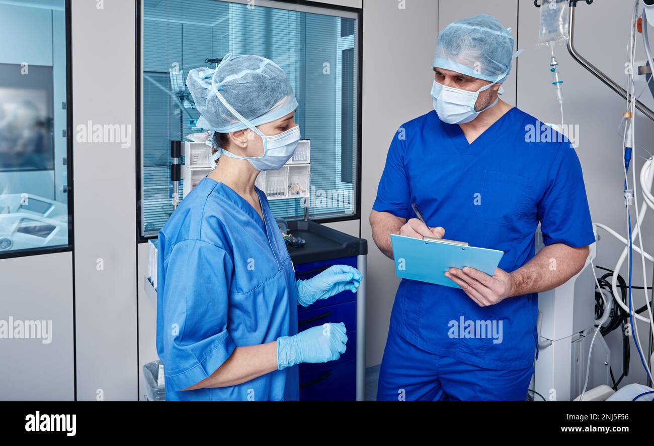 Krankenschwestern diskutieren Notizen mit Vitalzeichen des Patienten auf der Intensivstation des Krankenhauses während des Arbeitstages Stockfoto