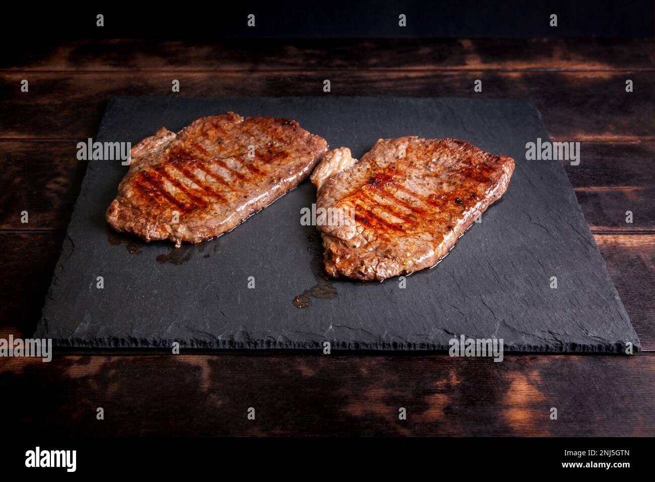 Gegrilltes Minutensteak mit Marmorfleisch auf einem Steinschieferbrett. Stockfoto