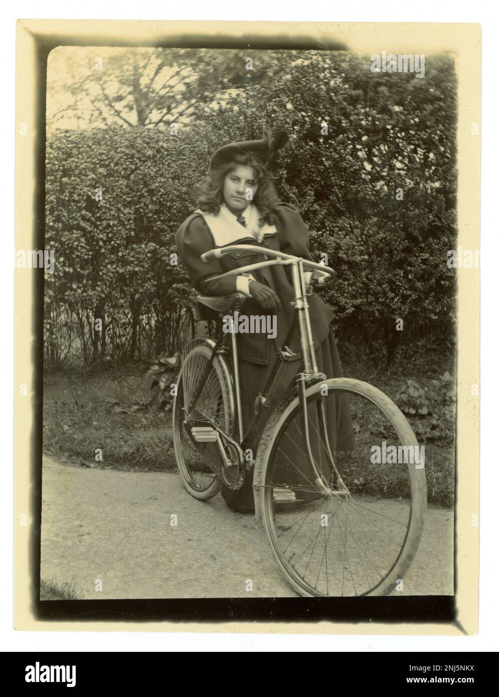 Originales viktorianisches Foto einer Teenagerin mit ihrem Fahrrad in einem Garten, mit Baskenmütze, Vintage-Radfahren, um 1897, viktorianisches Mädchen. Worcester Area, USA K Stockfoto