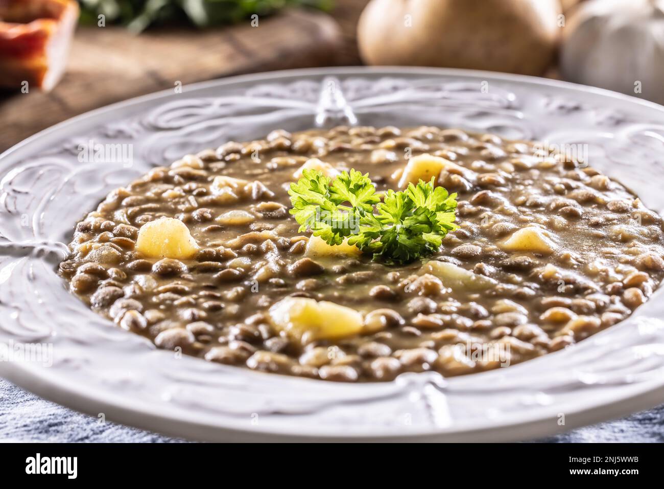 Linsen- und Kartoffelsuppe oder Eintopf auf einem rustikalen Teller mit Petersilie. Stockfoto