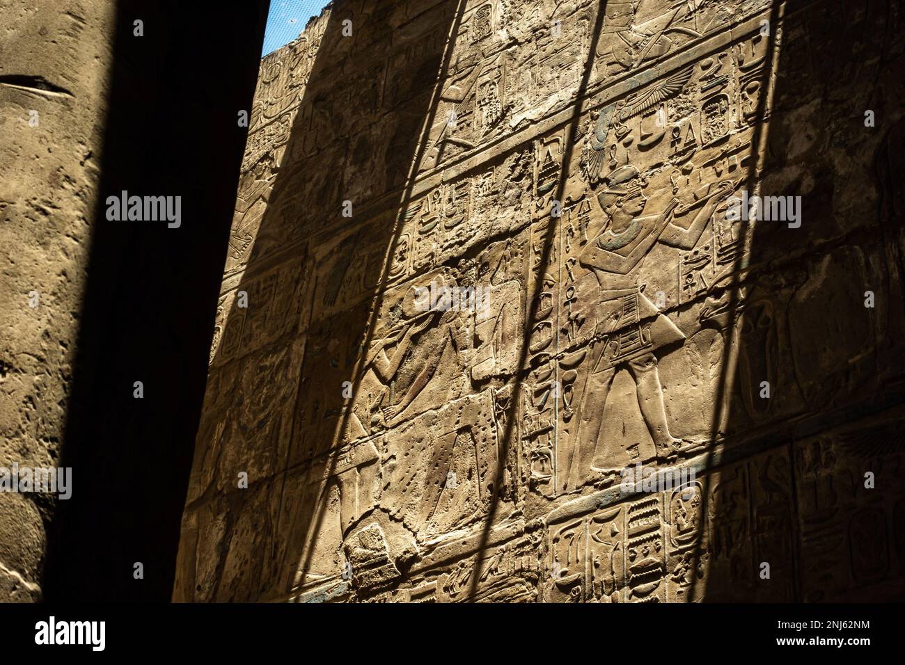 Hieroglyphen an einer Wand im Luxor-Tempel. Sonne erzeugt harte Schatten auf der Wand. Teilweise lackiert. Stockfoto