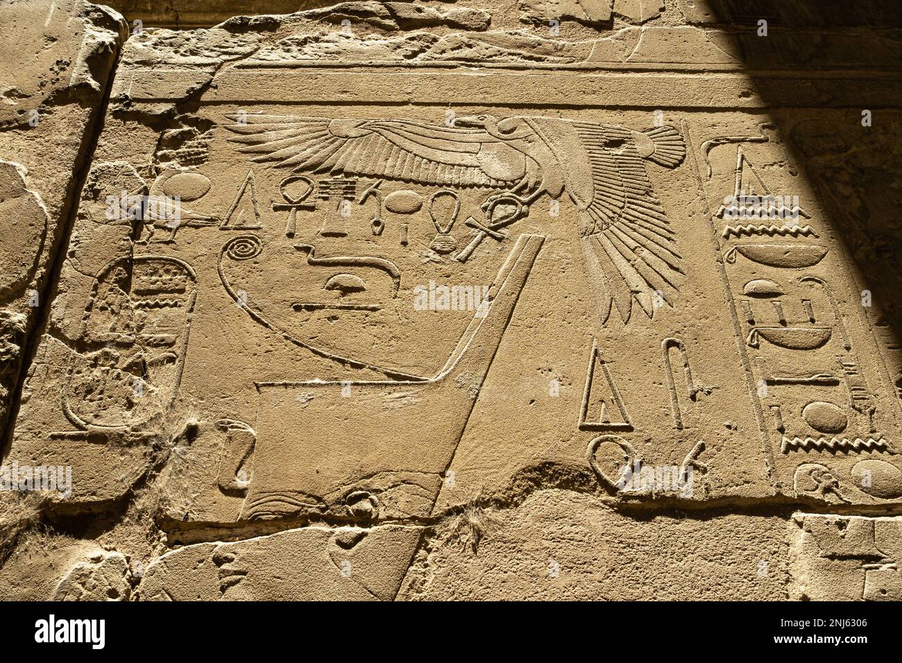 Hieroglyphen und Relief eines Geiers an einer Wand im Luxor-Tempel. Starke Kontraste aufgrund der niedrigen Sonne Stockfoto