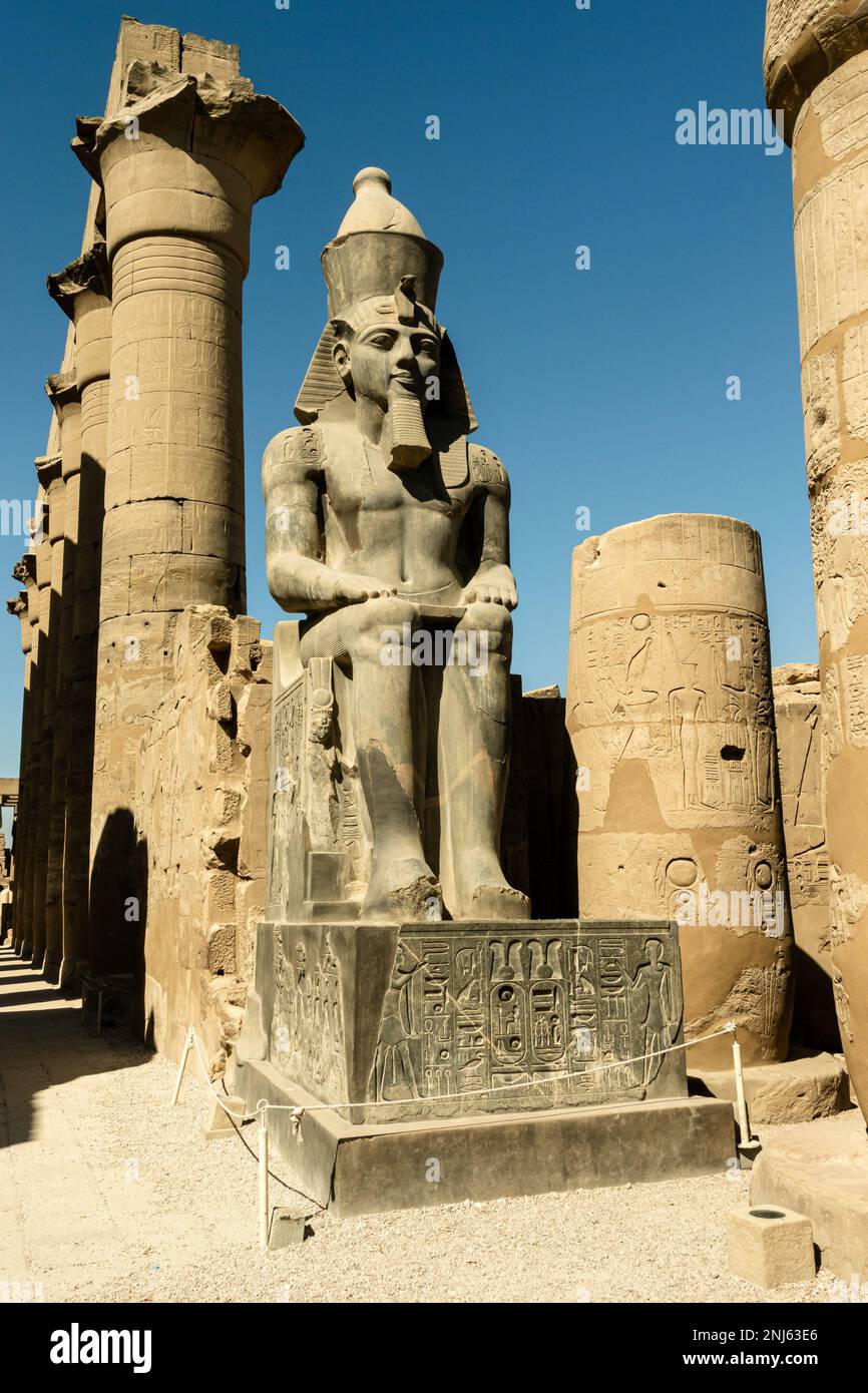 Ramses sitzt im großen Innenhof des Tempels von Luxor, Ägypten. Tron mit Hieroglyphen. Stockfoto