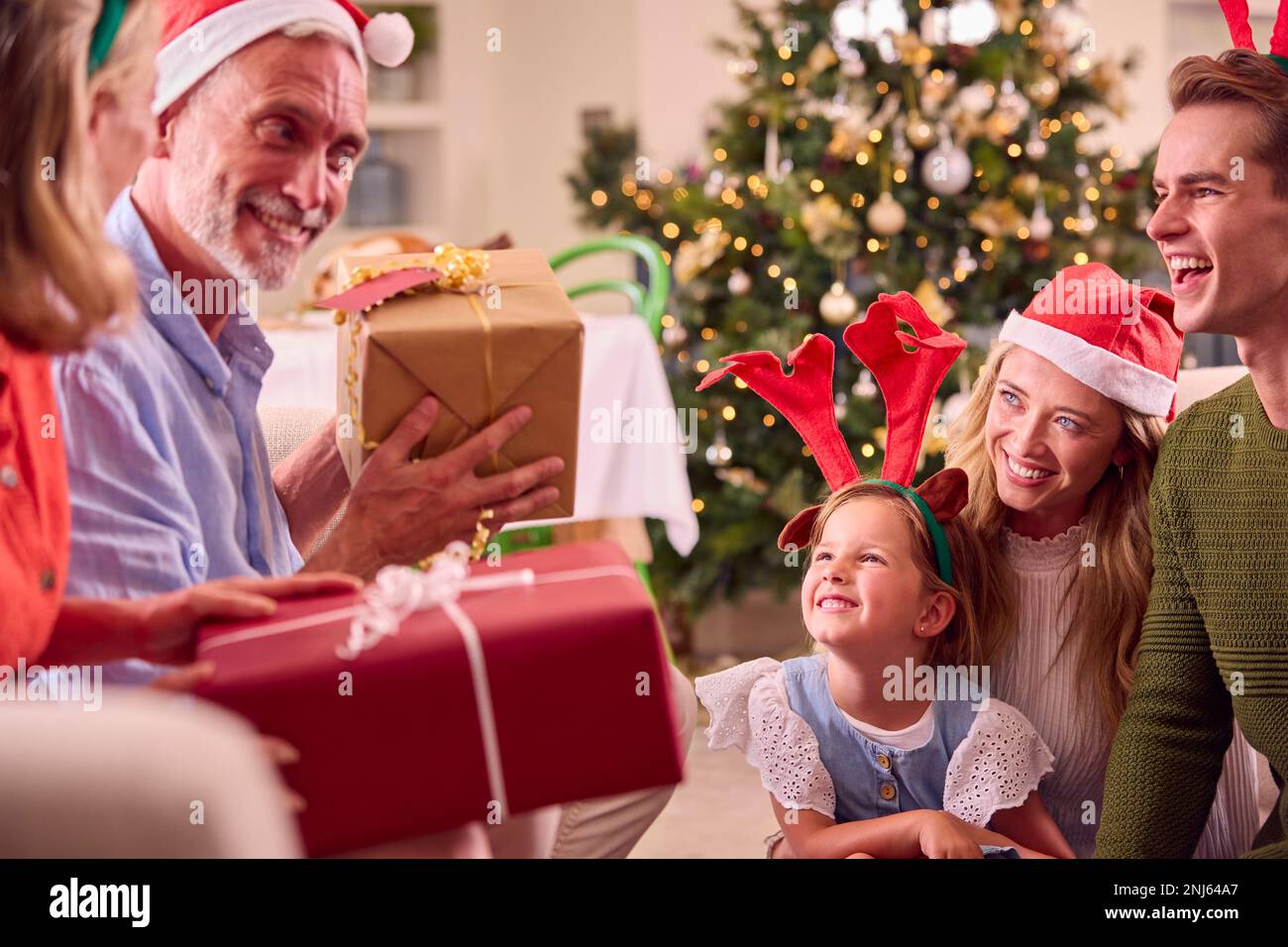 Die Familie Mehrerer Generationen Feiert Weihnachten Zu Hause Mit Weihnachtsmannmützen Und Antlers Eröffnungsgeschenken Stockfoto