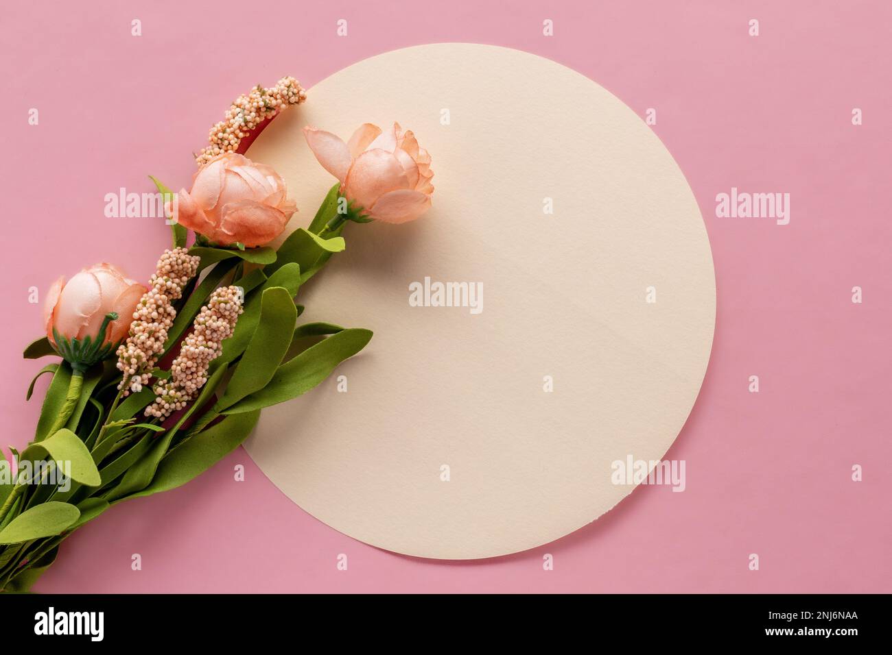 Flacher Blumendruck mit rundem Platz für Kopien und Seidenrosen auf weichem pinkfarbenen Hintergrund Stockfoto