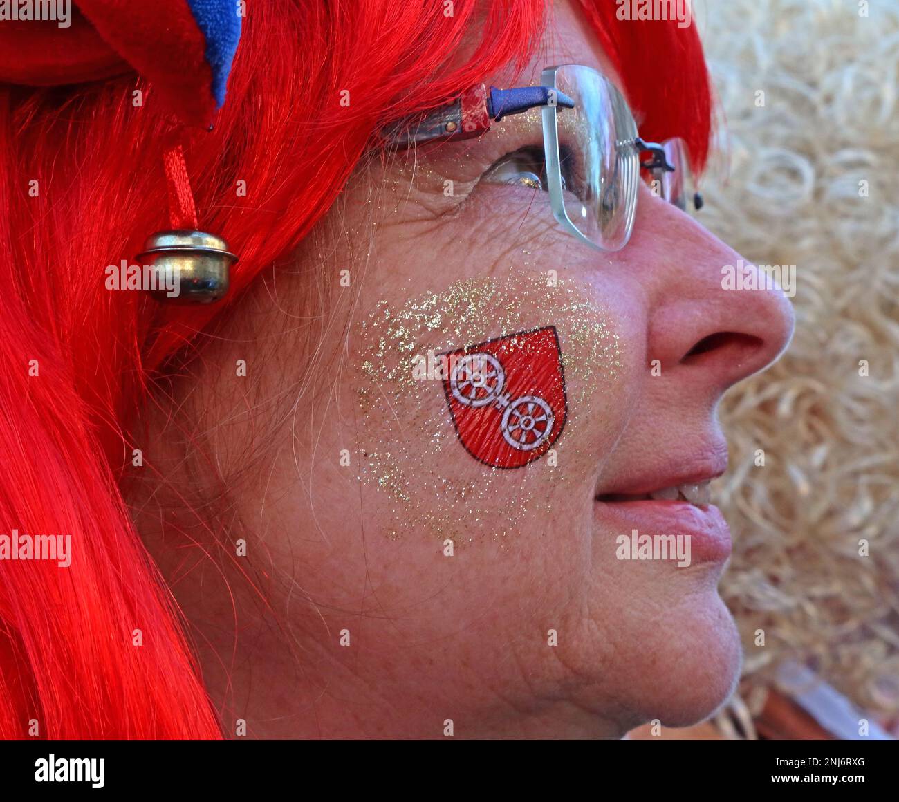 Genießen Sie die Mainz Fastnacht, Shrove Monday, Frau in einer roten Perücke mit temporärem Tattoo in Rot auf das Wappen der Stadt, Februar 2023 Stockfoto