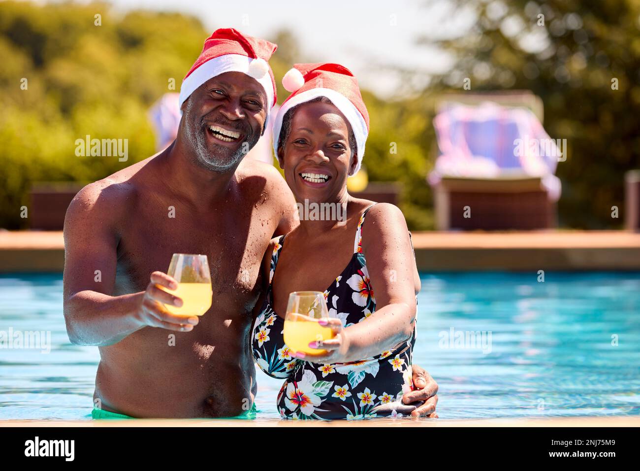 Porträt Eines Seniorenpaares In Den Weihnachtsferien Im Schwimmbad Mit Weihnachtsmänteln Stockfoto