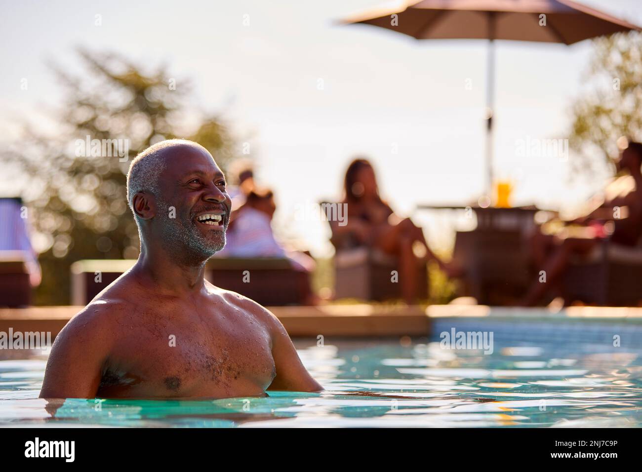 Lächelnder Seniorenmann Im Sommerurlaub, Entspannend Im Swimmingpool Stockfoto