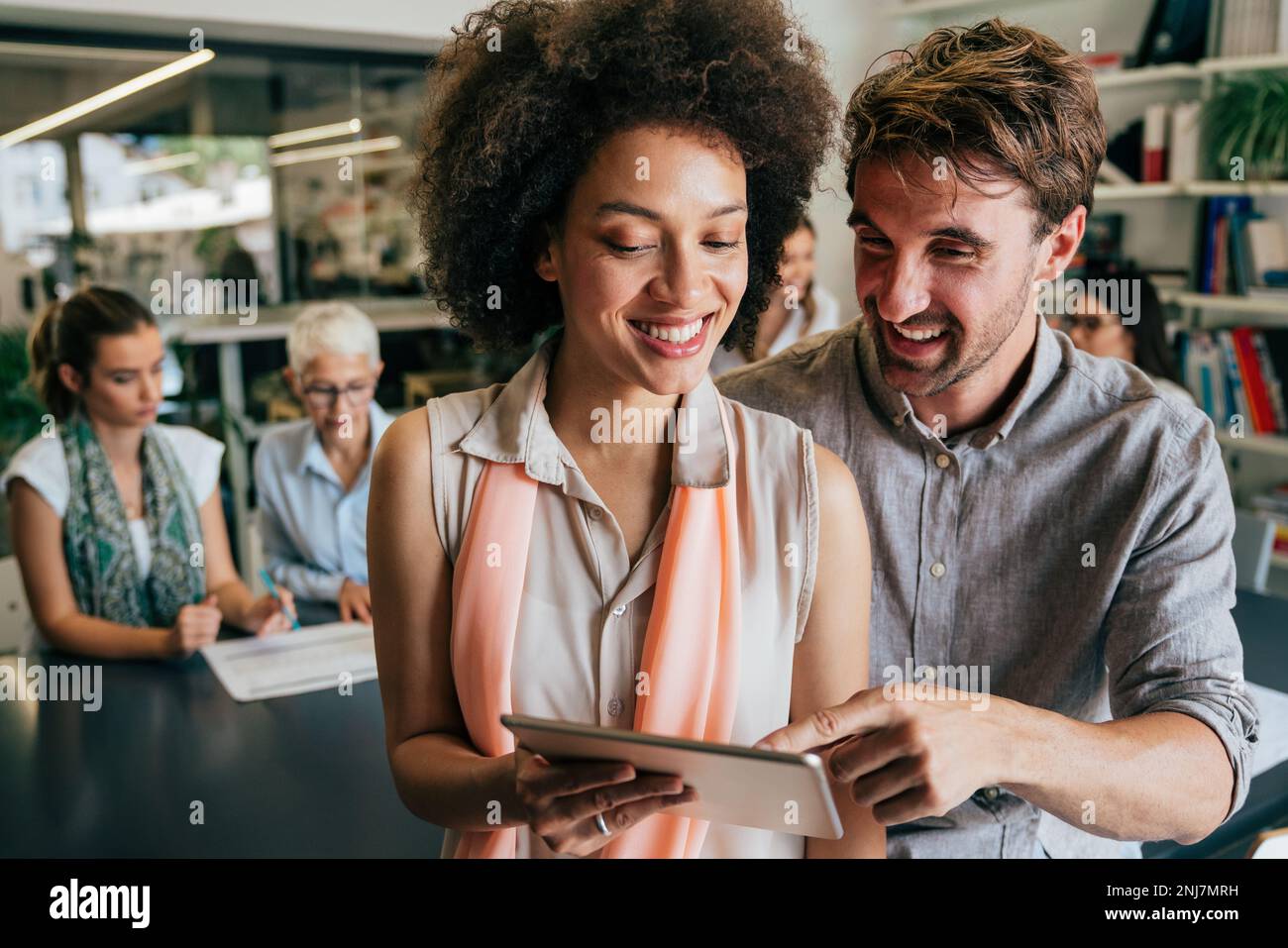 Lächelnd treffen sich verschiedene Kollegen in einem Brainstorming in der Vorstandsetage, um gemeinsam Finanzstatistiken zu diskutieren Stockfoto