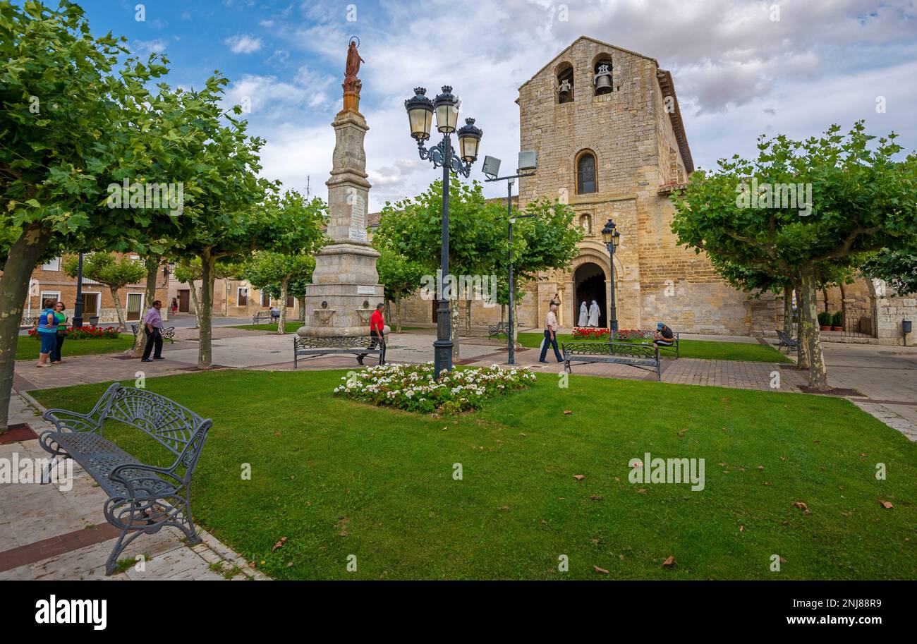 Auf dem Jakobsweg spazieren die Menschen um eine gestaltete plaza de Carrion de los Condes herum, auf der eine Statue und die Kirche Santa Maria del Camino zu sehen sind Stockfoto