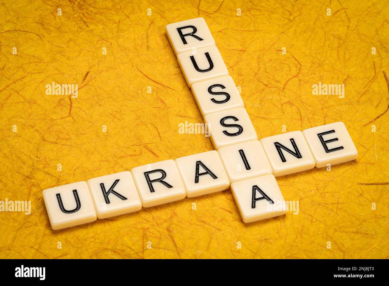 Kreuzworträtsel der Ukraine und Russlands in Elfenbein-Buchstabenkacheln gegen strukturiertes handgefertigtes Papier Stockfoto