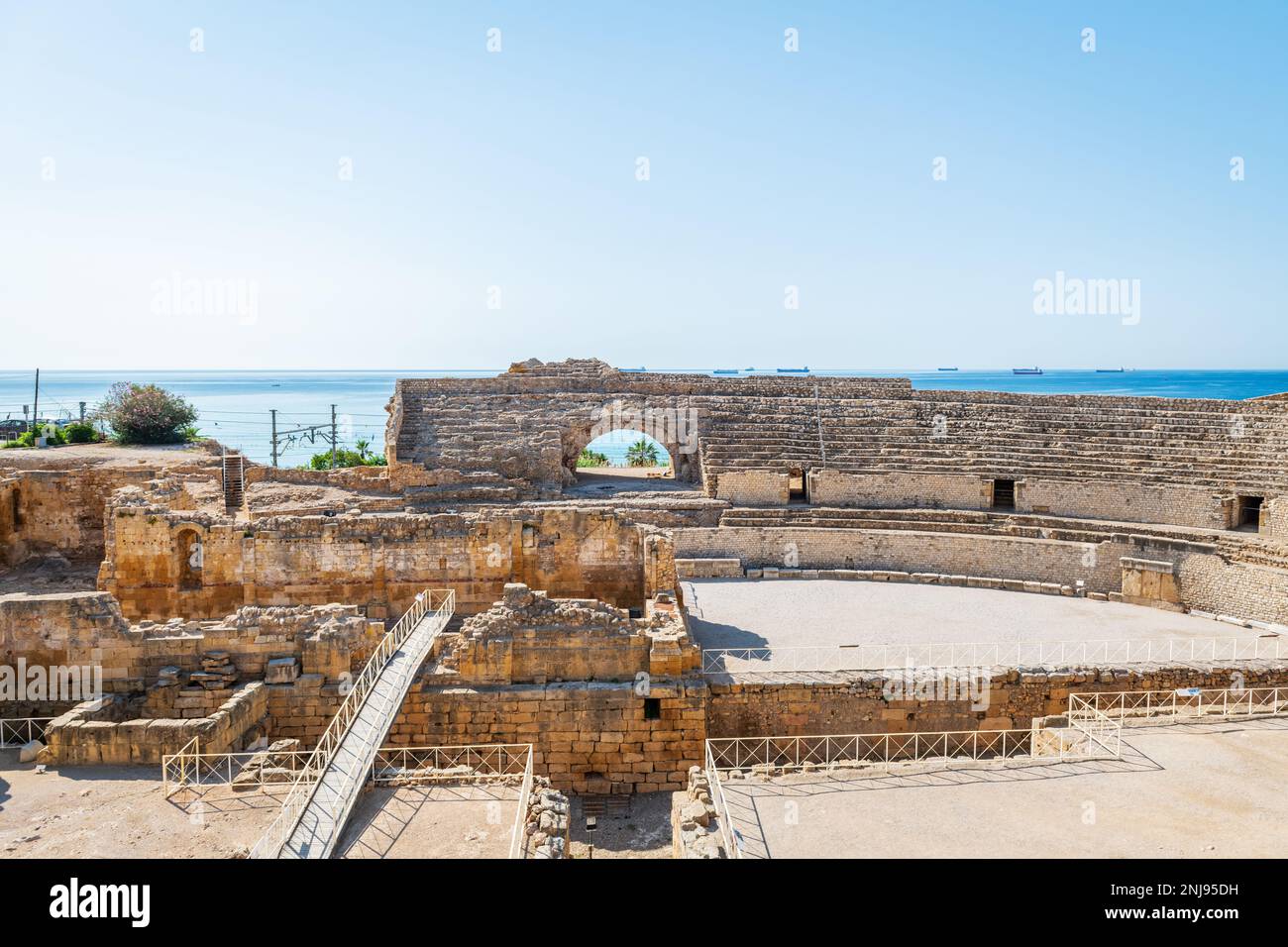 Weitwinkelblick auf die Ruinen des römischen Amphitheaters in Tarragona, erbaut im 2. Jahrhundert v. Chr., mit dem Mittelmeer im Hintergrund. Stockfoto