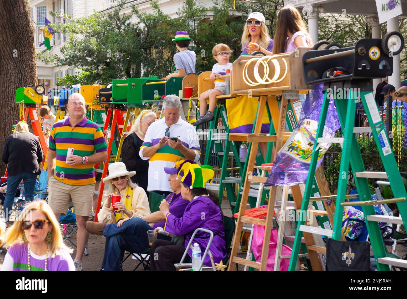 Die Einwohner von New Orleans warten auf die Mardi Gras Rex Parade auf der St. Charles Ave in New Orleans. Eltern machen die Leitersitze für ihre Kinder. Stockfoto