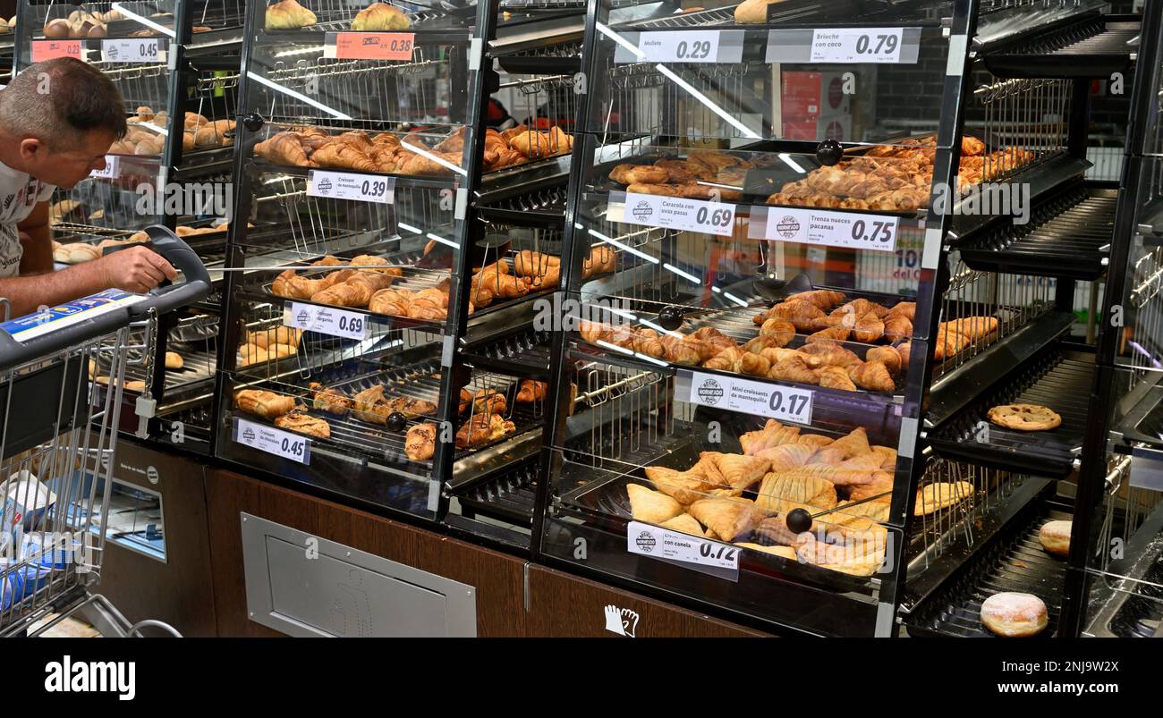 Regale im Supermarkt mit rückseitigen Waren, bei denen der Kunde mit einem Zauberstab aus dem Regal manipuliert, um die Artikel nicht zu handhaben Stockfoto