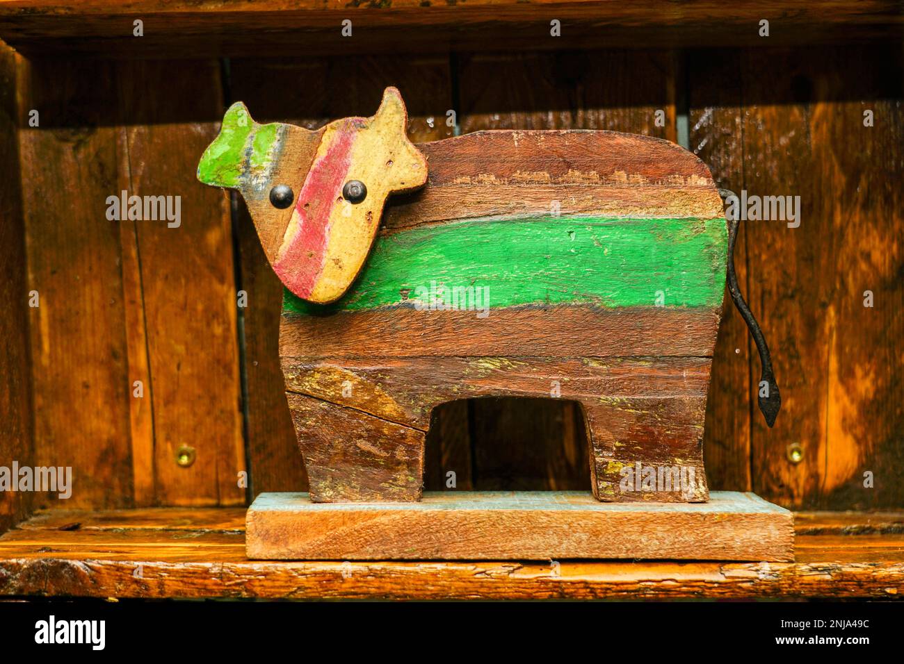 Gemalte einfache lustige Holzkuh-Figur als altes Innenelement auf braunen Holzbrettern Stockfoto