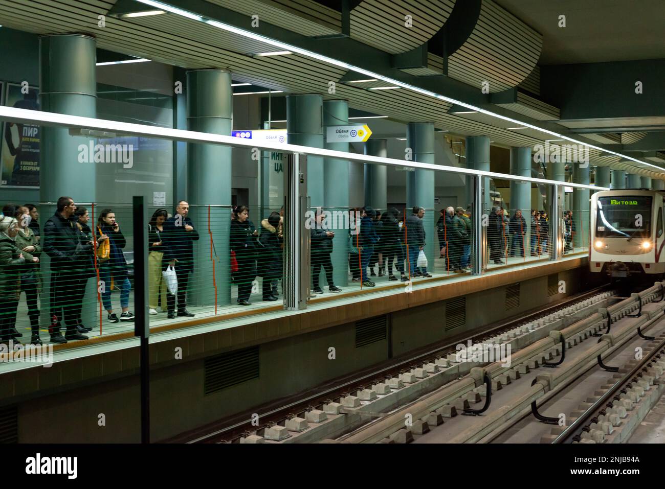 Personen, die auf einen Zug hinter automatischen vertikalen Bahnsteig-Windschranken warten, die als Vorbeugungs- und Sicherheitsmaßnahme für die Passagiere nach oben klappen. Blick auf U-Bahn-, U-Bahn- oder U-Bahn-Station in Sofia, Bulgarien, Osteuropa, Balkan, EU Stockfoto