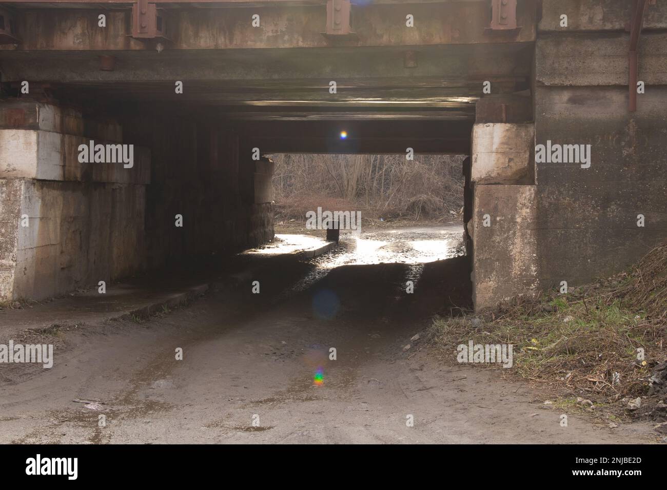 Silhouette eines Mannes, der unter einer Eisenbahnbrücke vorbeifährt Stockfoto