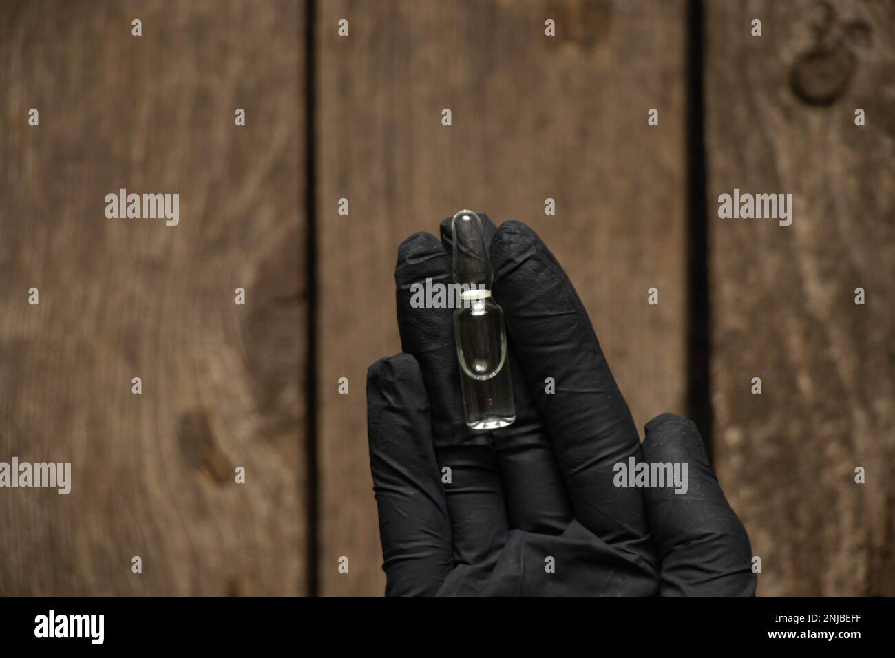 Die Hand in Handschuhen hält eine Ampulle mit Medikamenten Stockfoto