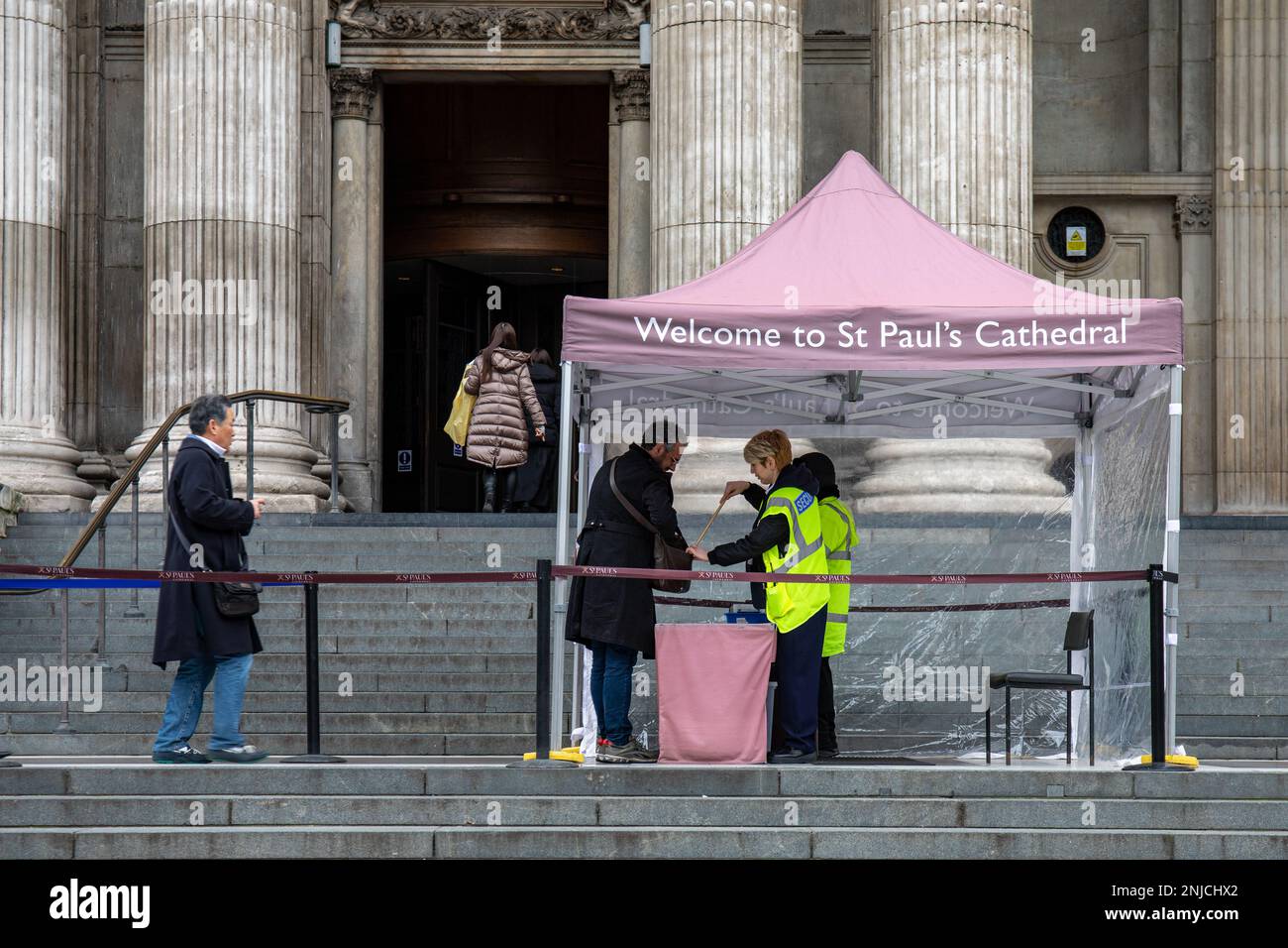 Suche nach Besuchertaschen durch Sicherheitspersonal an der Sicherheitskontrolle vor der St Paul's Cathedral in London, England Stockfoto