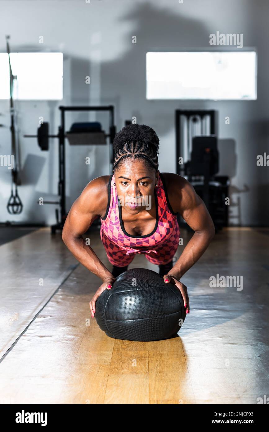 Entschlossene Frau, die mit einem Ball im Fitnessstudio Unterstützung leistet. Wirbelsäule und Arme stärken. Stockfoto