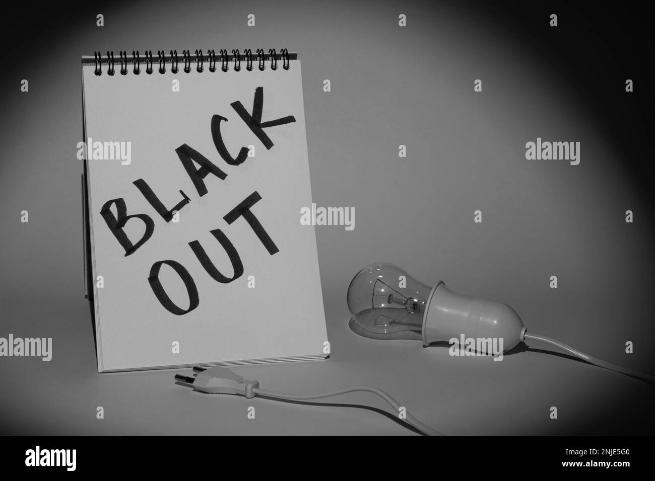 Notebook mit der Aufschrift „Blackout“ und einer elektrischen Glühlampe mit einer Halterung und einem Stecker auf grauem Hintergrund, beleuchtet durch eine Taschenlampe Stockfoto Notebook mit der Aufschrift „Blackout“ und einer elektrischen Glühlampe mit einer Halterung und einem Stecker auf grauem Hintergrund, beleuchtet durch eine Taschenlampe Stockfoto