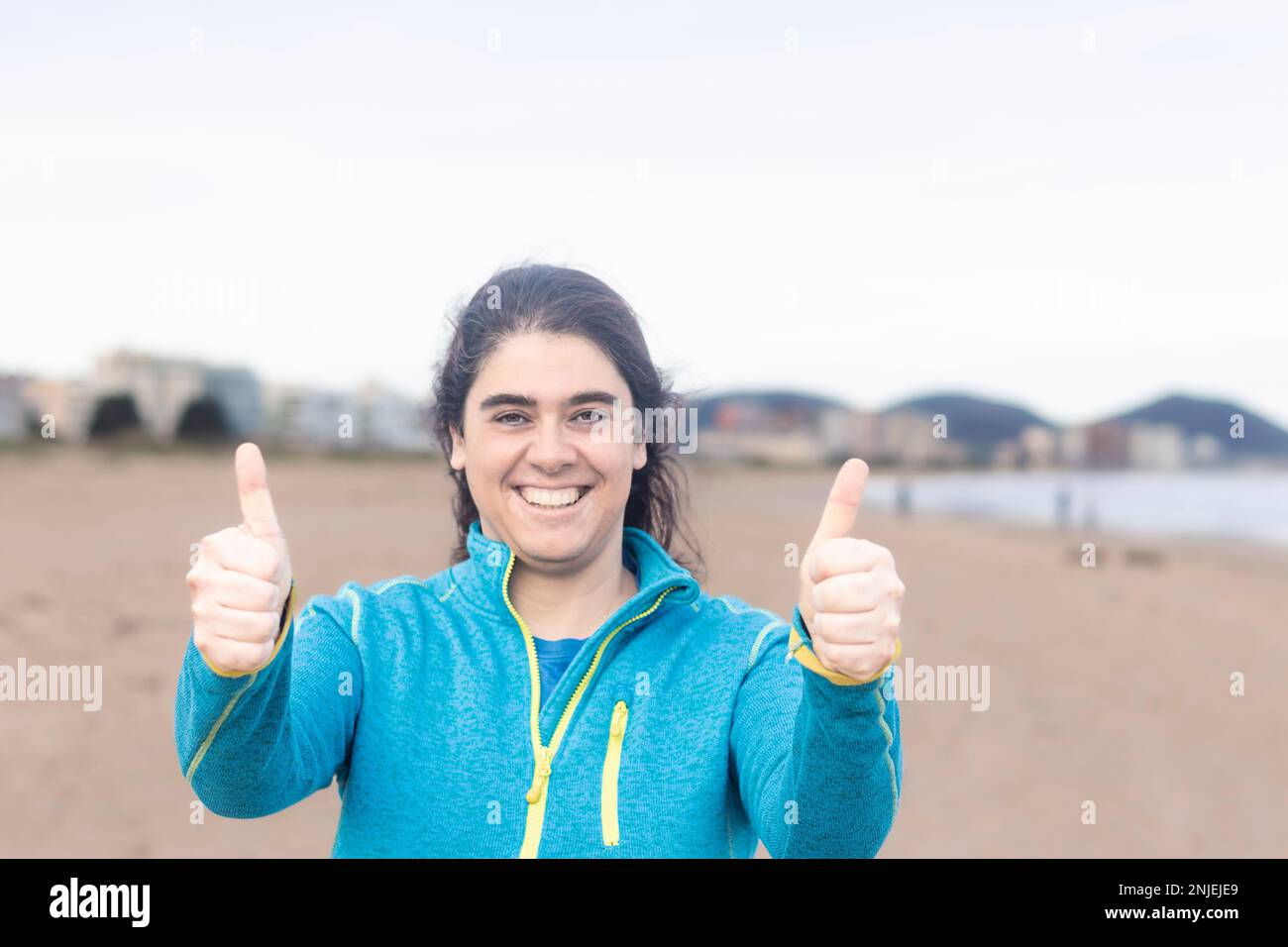 Hispanische Frau, die mit der Hand fröhliche Daumen-hoch-Geste macht. Genehmigender Ausdruck, der auf die Kamera schaut und Erfolg zeigt. Stockfoto