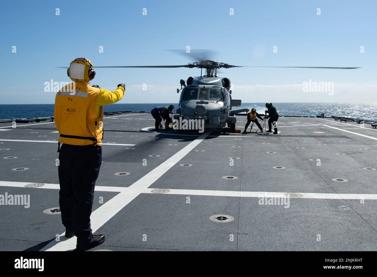 230218-N-MK318-1187 OSTPAZIFIK (18. Feb. 2023) Boatswain's Mate 2. Klasse Sam Peterson, links, Blauer Matrose Segelschiff an Bord des Kampfschiffs USS Mobile (LCS 26) der Independence-Variante, Handzeichen zur Kreide und Kette eines MH-60R Hubschraubers, befestigt an Helicopter Maritime Strike Squadron 49 (HSM 49), Am 18. Februar im Cockpit des Schiffes. Küstenschiffe sind schnelle, optimal bemannte, auf die Mission zugeschnittene Bodenkombattanten, die in küstennahen und offenen Meeresumgebungen operieren und gegen die Bedrohungen der Küste des 21. Jahrhunderts gewinnen. Mobile führt derzeit Routineeinsätze i durch Stockfoto